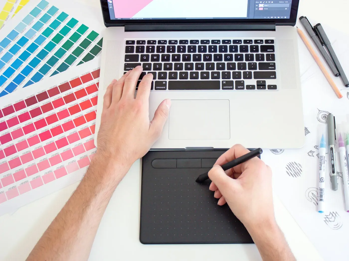 Diseñador trabajando con tableta gráfica y muestrario de colores